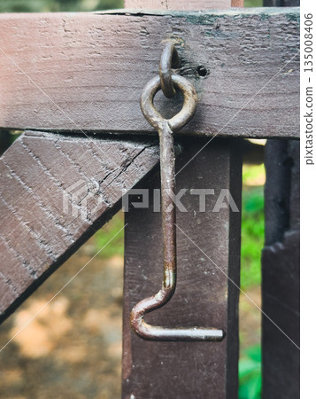 Rusty hook latch on a wooden gate in a countryside setting. Rusty hook latch on a wooden gate in a countryside setting. 135008406