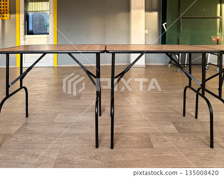 Two folding tables in an empty room with wood flooring. Two folding tables in an empty room with wood flooring. 135008420