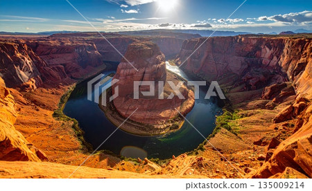 A breathtaking sunset illuminates the red rock cliffs and desert landscape of Grand Canyon National Park in Arizona, offering a grand view of the valley and mountains under a cloudy sky 135009214