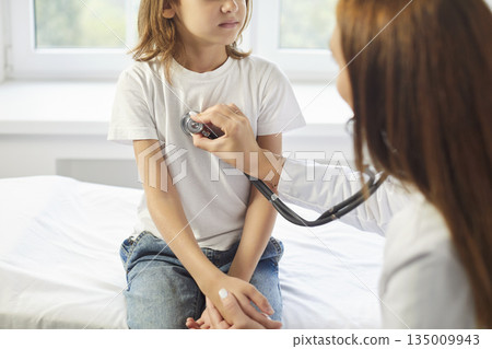 Paediatrician doctor using stethoscope listening heart sounds lungs of little boy patient 135009943
