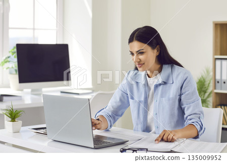 Woman Working with Papers and Laptop in Office or Home Woman Working with Papers and Laptop in Office or Home 135009952