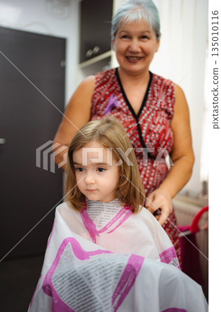 Little girl getting haircut in hairdresser's salon chair 135010116