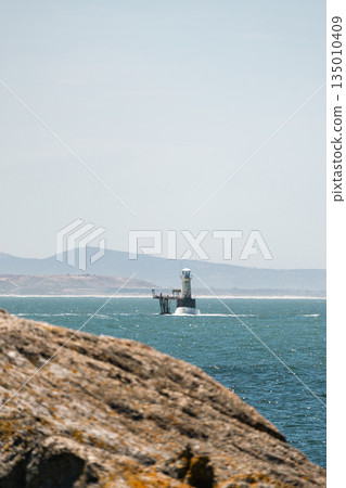 Lighthouse guides ships through rough sea, providing safety. Coastal navigation Lighthouse guides ships through rough sea, providing safety. Coastal navigation 135010409