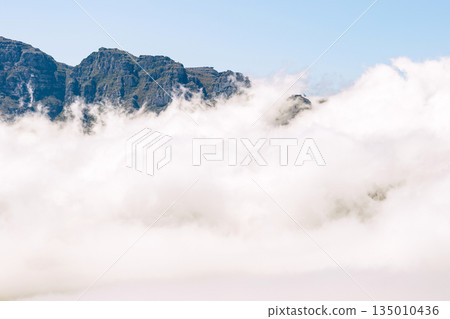 Foggy mountain landscape with clouds covering the lower part of the peak Foggy mountain landscape with clouds covering the lower part of the peak 135010436