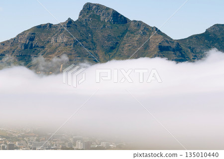 Rugged mountain peaks rise above a thick blanket of fog or cloud inversion Rugged mountain peaks rise above a thick blanket of fog or cloud inversion 135010440