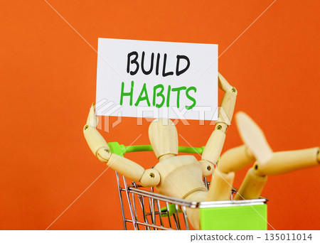Build habits symbol. Concept word Build habits on beautiful white paper. Beautiful wooden clothespin. Businessman's model. Beautiful orange background. Business build habits concept. Copy space. Build habits symbol. Concept word Build habits on beautiful white paper. Beautiful wooden clothespin. Businessman's model. Beautiful orange background. Business build habits concept. Copy space. 135011014