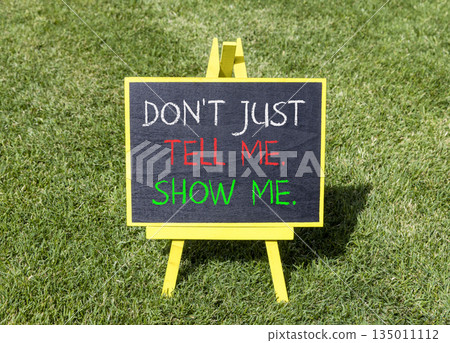 Tell or show symbol. Concept words Do not just tell me, show me on beautiful blackboard. Beautiful green grass lawn background. Business tell or show concept. Copy space. 135011112