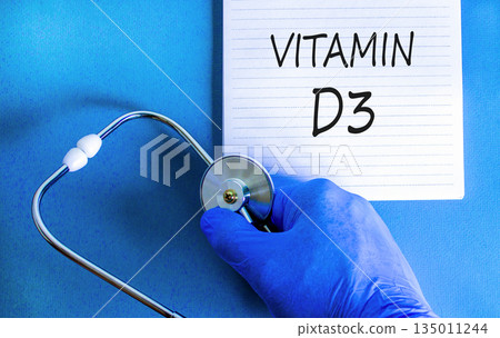 Vitamin D3 symbol. Concept words Vitamin D3 on beautiful white note. Doctor's hand in blue medical glove. Stethoscope. Beautiful blue background. Medical healthy lifestyle Vitamin D3 concept. Vitamin D3 symbol. Concept words Vitamin D3 on beautiful white note. Doctor's hand in blue medical glove. Stethoscope. Beautiful blue background. Medical healthy lifestyle Vitamin D3 concept. 135011244