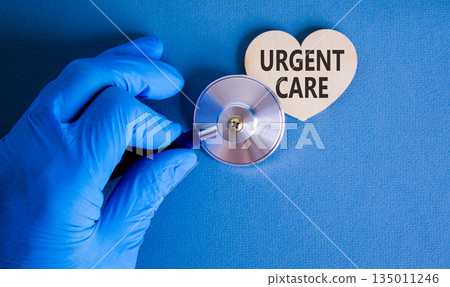 Urgent care symbol. Concept words Urgent care on beautiful wooden heart. Doctor's hand in blue medical glove. Stethoscope. Beautiful blue background. Medical healthy lifestyle urgent care concept. Urgent care symbol. Concept words Urgent care on beautiful wooden heart. Doctor's hand in blue medical glove. Stethoscope. Beautiful blue background. Medical healthy lifestyle urgent care concept. 135011246