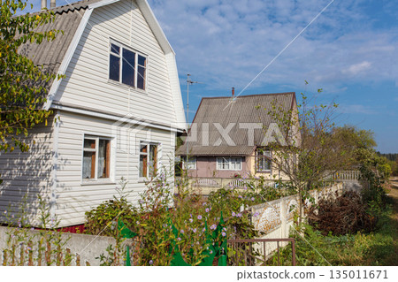 A small country house covered with plastic panels on a summer street. 135011671
