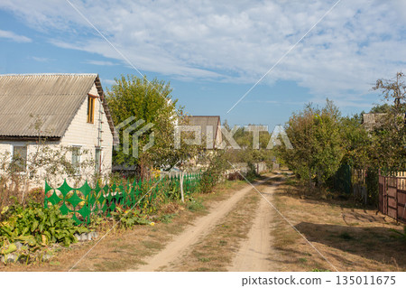 Landscape with a road passing through a deserted summer cottage village. 135011675