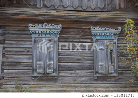 Two windows on a building with a wooden frame. The windows are open and the frame is old 135011715