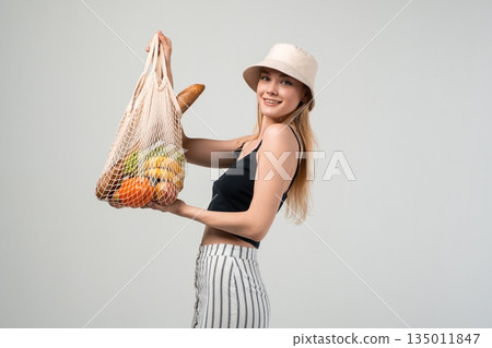 Eco lifestyle portrait of woman with reusable shopping bag full of fresh groceries, sustainable food and zero waste concept Eco lifestyle portrait of woman with reusable shopping bag full of fresh groceries, sustainable food and zero waste concept 135011847