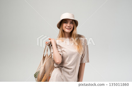 Young woman holding reusable mesh shopping bag with fresh vegetables and bread, minimal sustainable lifestyle, eco friendly shopping and healthy food choices Young woman holding reusable mesh shopping bag with fresh vegetables and bread, minimal sustainable lifestyle, eco friendly shopping and healthy food choices 135011860