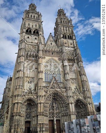 Flamboyant Gothic facade of Tours Cathedral Saint-Gatien in France. The massive stone structure features twin towers, intricate tracery, and a large central rose window. Classic medieval craftsmanship 135012611