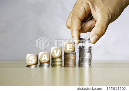 Saving money concept with stacked coins and blocks spelling "SAVE," symbolizing financial growth, investment, and smart money management. Saving money concept with stacked coins and blocks spelling "SAVE," symbolizing financial growth, investment, and smart money management. 135013302