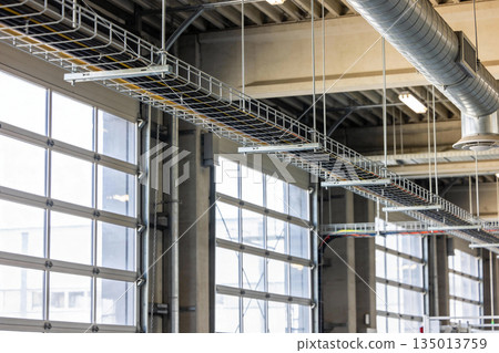 Industrial building interior with overhead cable trays and large glass garage doors 135013759