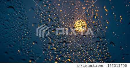 Raindrops on glass with glowing street light bokeh at night. 135013796