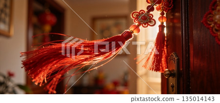 Traditional red Chinese knot tassel decoration backlit by sunlight. Close up of festive Lunar New Year ornament with glowing threads. Spring Festival celebration concept 135014143