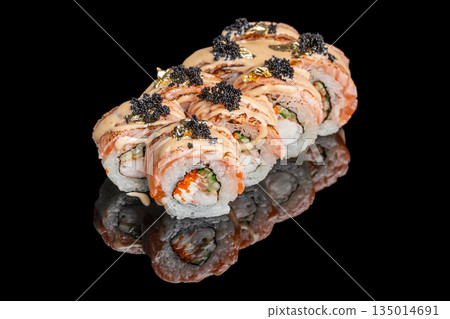 Luxury sushi roll with salmon, cream cheese and cucumber topped with black caviar and gold flakes isolated on black background with reflection 135014691
