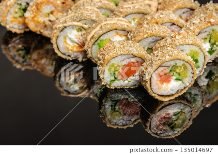 Fried sushi rolls with salmon shrimp and cream cheese close up on dark background 135014697