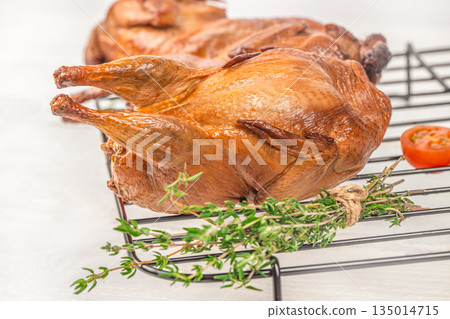 Roasted quail with crispy golden skin on cooling rack with thyme 135014715