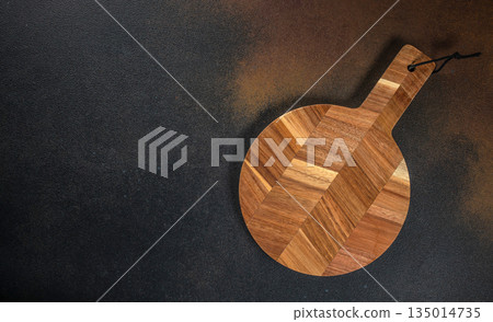 Round wooden cutting board on dark background, top view, copy space 135014735