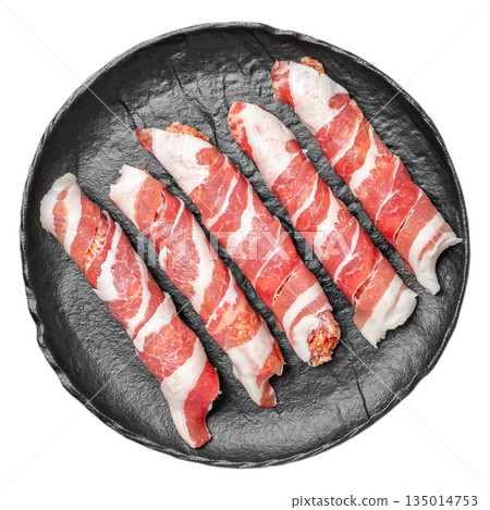 Raw bacon wrapped meat rolls on black plate isolated on white background 135014753