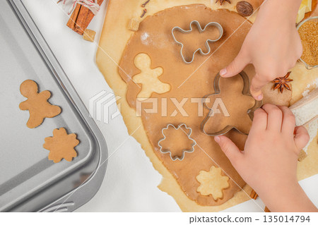 Children cutting gingerbread cookies from dough with cutters on kitchen table, top view, free space for text Children cutting gingerbread cookies from dough with cutters on kitchen table, top view, free space for text 135014794