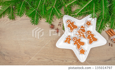 Gingerbread cookies with icing in star shaped plate and Christmas decorations on wooden background, top view, free space for text Gingerbread cookies with icing in star shaped plate and Christmas decorations on wooden background, top view, free space for text 135014797