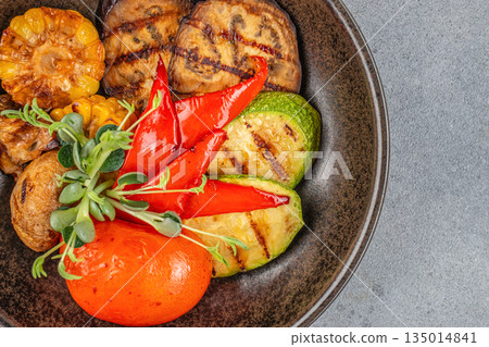 Grilled vegetables with corn, peppers, and zucchini on a dark plate Grilled vegetables with corn, peppers, and zucchini on a dark plate 135014841