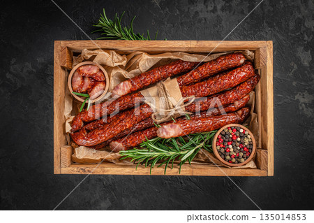 Smoked sausages with herbs and spices in a wooden box with copy space on dark background 135014853