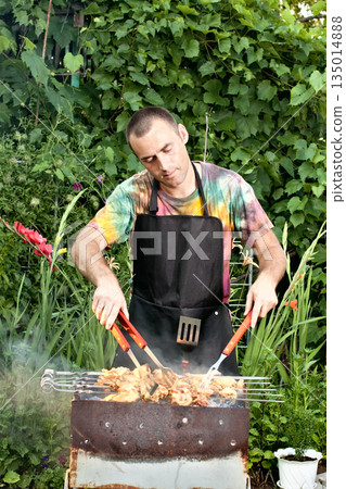 Man grilling shashlik on a charcoal barbecue grill Man grilling shashlik on a charcoal barbecue grill 135014888