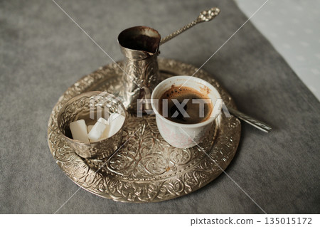 Freshly brewed Bosnian coffee in a small cup on an ornate metal tray. Concept of tradition, cultural heritage and calm daily moment Freshly brewed Bosnian coffee in a small cup on an ornate metal tray. Concept of tradition, cultural heritage and calm daily moment 135015172