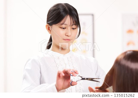 年輕女理髮師正在幫顧客剪頭髮 135015262
