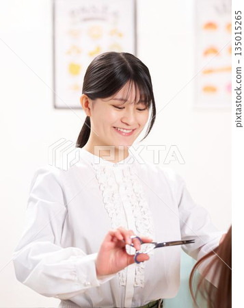 理髮師一邊和顧客聊天一邊剪頭髮。 135015265