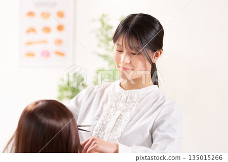 年輕女理髮師正在幫顧客剪頭髮 135015266