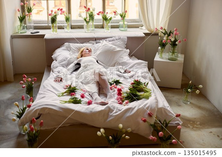 Serene bride in floral setting, Calm bride lying peacefully surrounded by vibrant tulip blossoms 135015495
