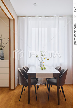 Charming breakfast nook featuring soft curtains and wooden accents Charming breakfast nook featuring soft curtains and wooden accents 135015710