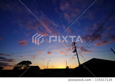 夕陽西下，暮色降臨，電線的輪廓清晰可見，寧靜的城市景觀，一天的結束 135017226