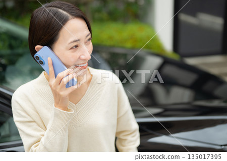 手持智慧型手機的女子,正在進行汽車估價 手持智慧型手機的女子,正在進行汽車估價 135017395