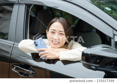 手持智慧型手機的女子,正在進行汽車估價 手持智慧型手機的女子,正在進行汽車估價 135017399