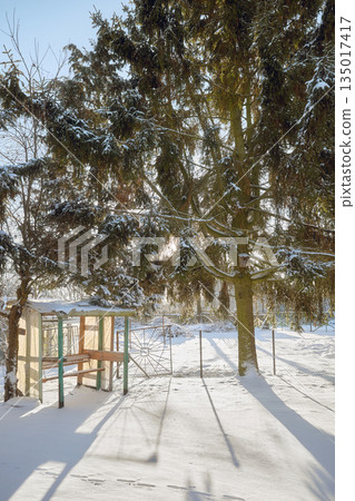 Tranquil winter countryside scene with a swing in the garden on a sunny day. Tranquil winter countryside scene with a swing in the garden on a sunny day. 135017417