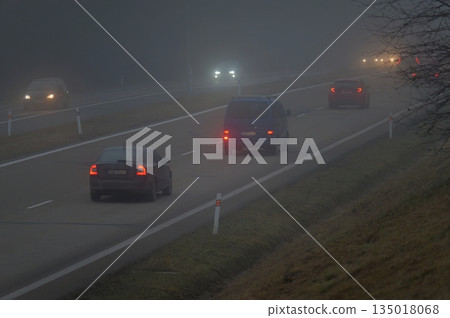 Cars in the fog. Bad winter weather and dangerous automobile traffic on the road. Light vehicles in foggy day. Cars in the fog. Bad winter weather and dangerous automobile traffic on the road. Light vehicles in foggy day. 135018068