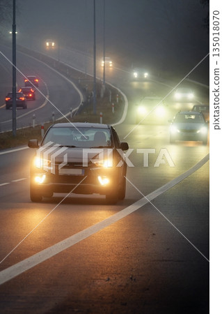 Bright headlights of a car driving on foggy winter road Bright headlights of a car driving on foggy winter road 135018070