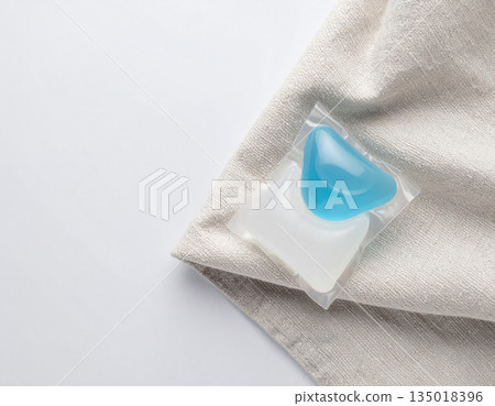 Cleaning products. Soluble laundry detergent capsule on a neutral linen cloth with empty space for text. Cleaning products. Soluble laundry detergent capsule on a neutral linen cloth with empty space for text. 135018396