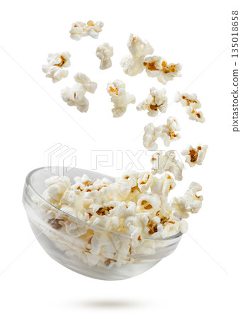 Popcorn flying out of a glass bowl close-up on a white. Isolated Popcorn flying out of a glass bowl close-up on a white. Isolated 135018658