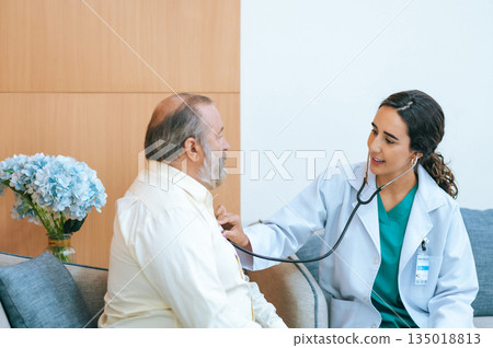Young female doctor in white medical coat attending physician using stethoscope listening an old patient for checking heartbeat. Medicine and health care concept. cardiology concept. 135018813