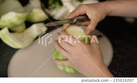 Woman's hands peeling and cutting winter melon on a cutting board 135019207