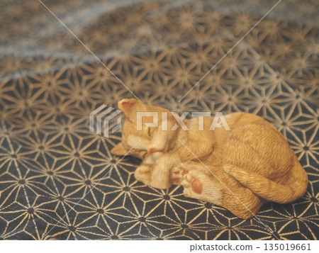 A cat figurine sleeping comfortably A cat figurine sleeping comfortably 135019661